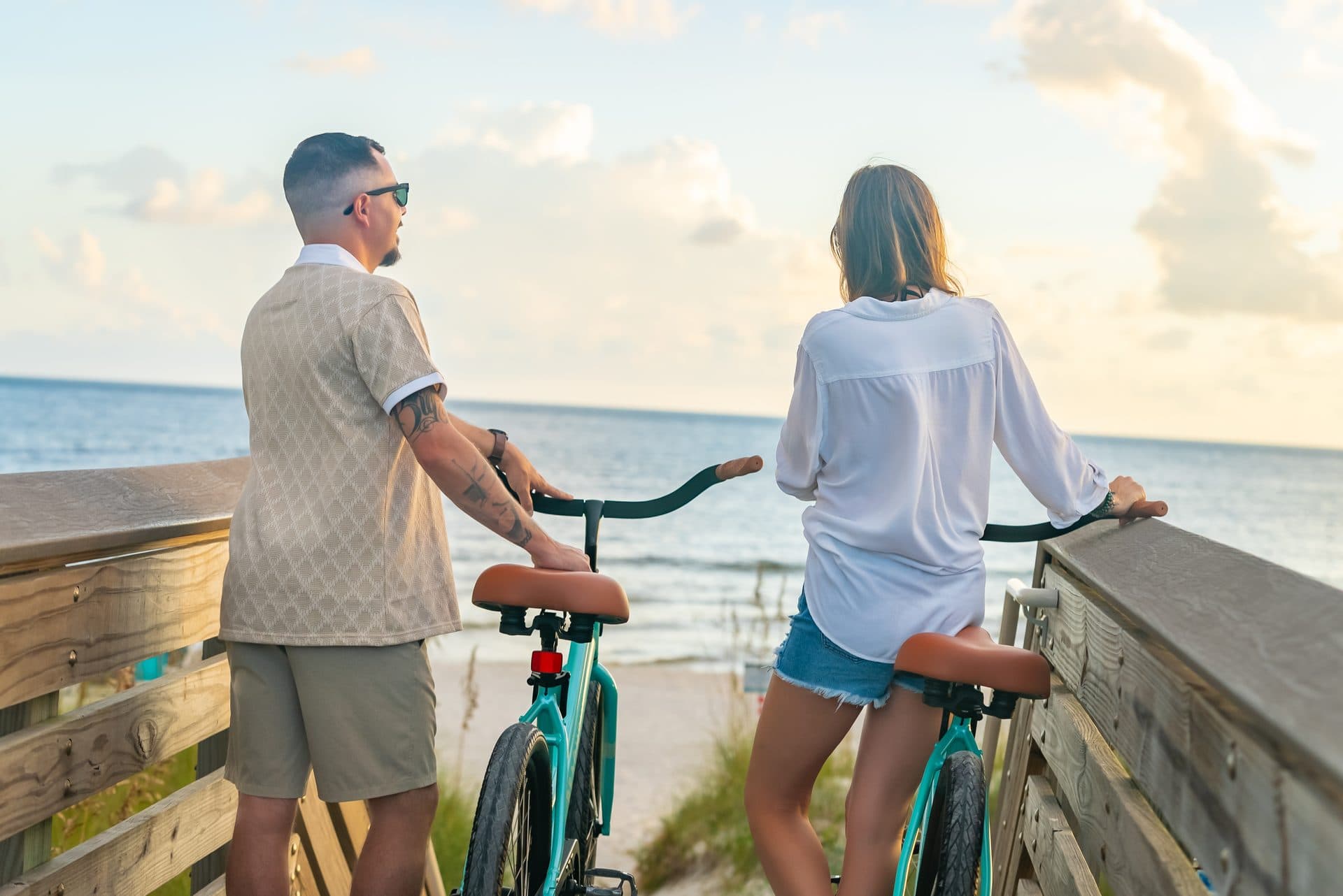 Couple with Beach Bikes on the boardwalk overlooking the ocean at sunset
